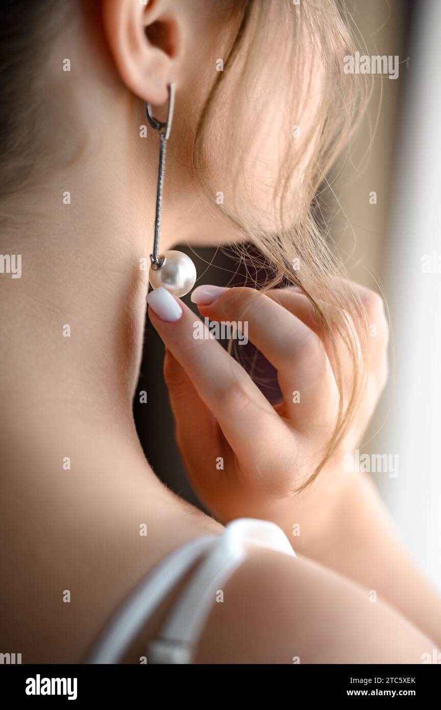 The morning of the bride's wedding, the bride touches her earrings. Stock Photo