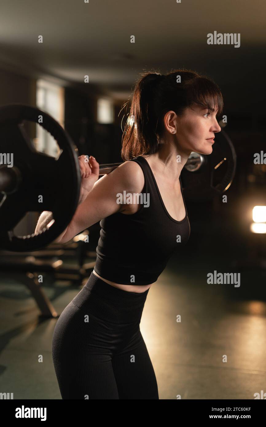 female bodybuilder holding heavy metal professional barbell, preparing