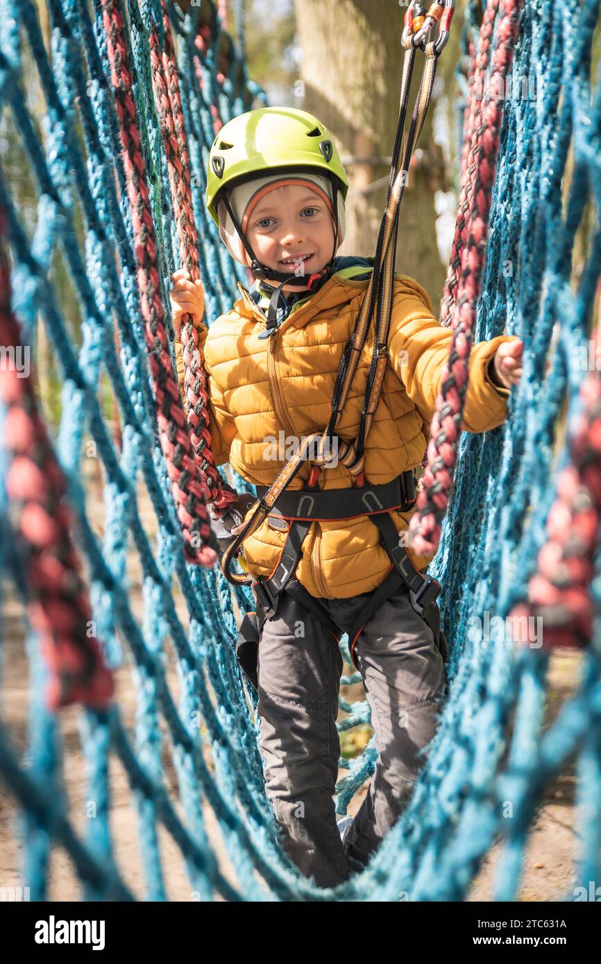 Portrait of cute little boy walk on the net in an adventure rope park Stock Photo