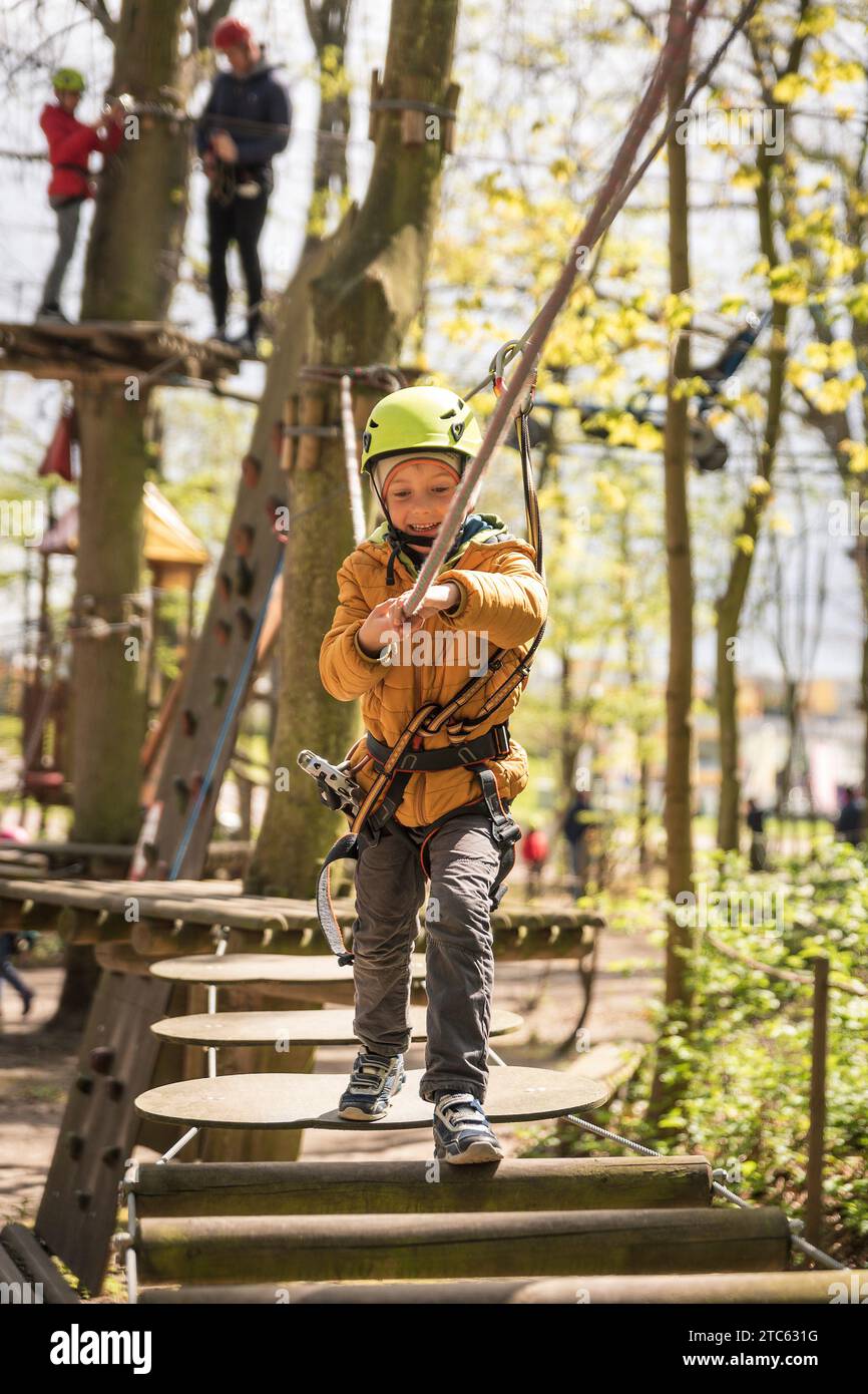 Portrait of cute little boy walk on a rope bridge in an adventure rope park Stock Photo