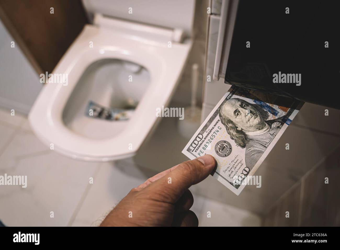 Flush money down toilet, throws dollar bills in the toilet, loss concept, close up, selective focus. concept of senseless waste of money, loss, useles Stock Photo