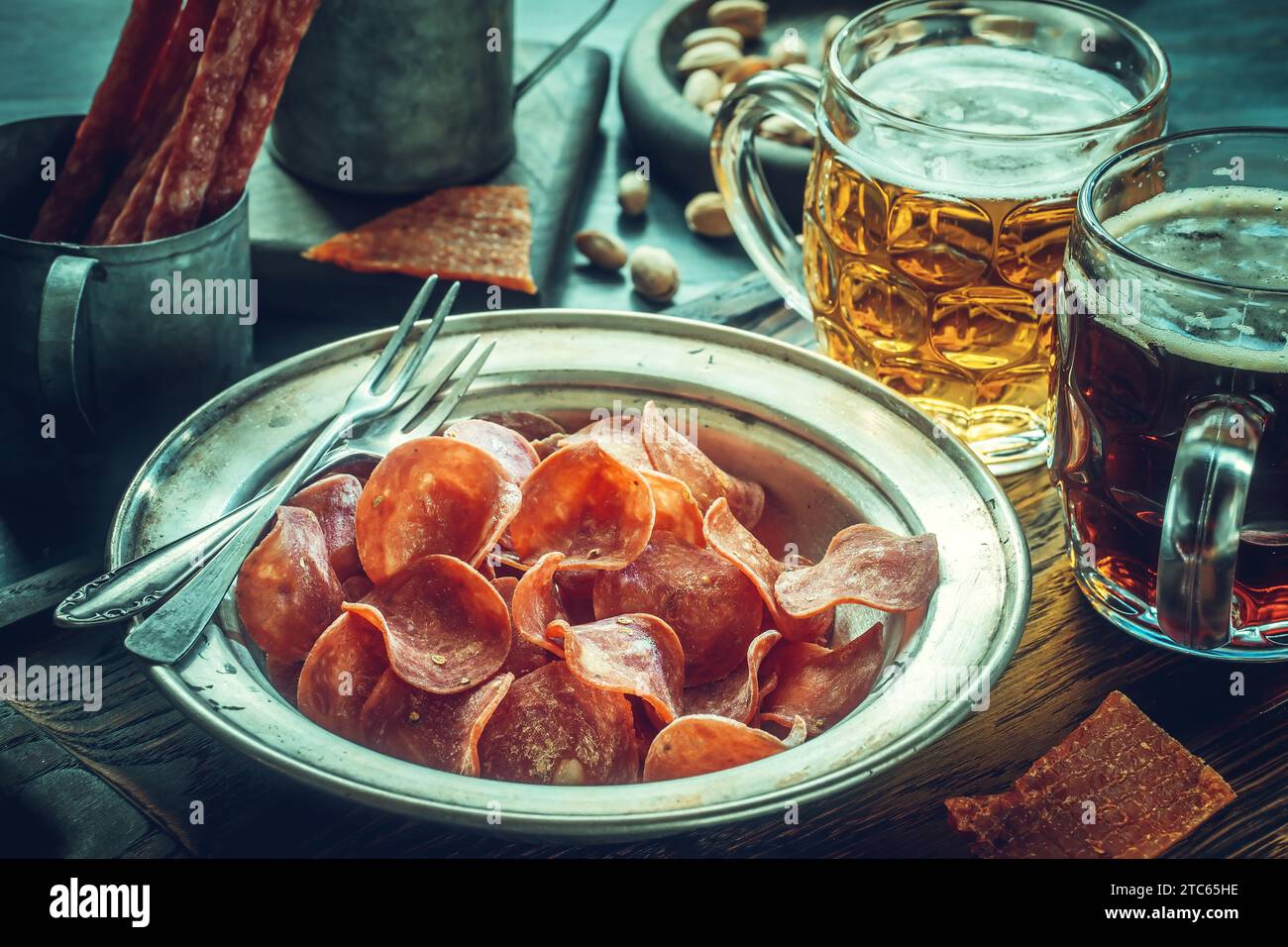 Jerky pork chips on vintage plate with beer on table. Dried meat slice Stock Photo