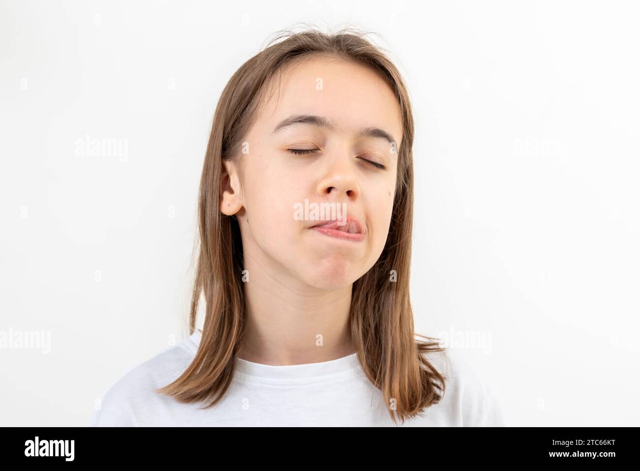 Funny teenage girl licks her lips on a white background isolated Stock