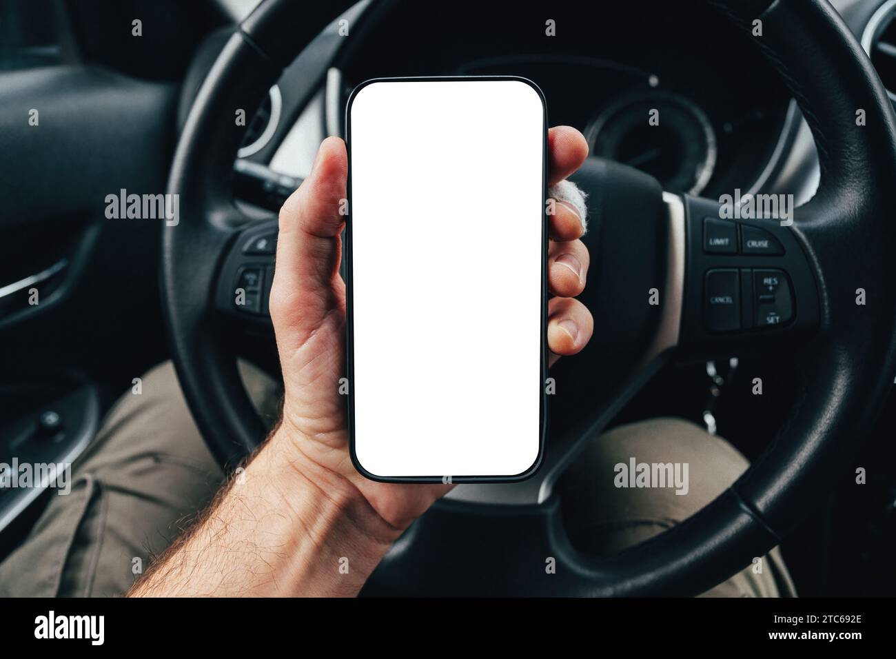 Driver app mockup with blank smartphone screen over steering wheel, man holding mobile phone device in car, selective focus Stock Photo