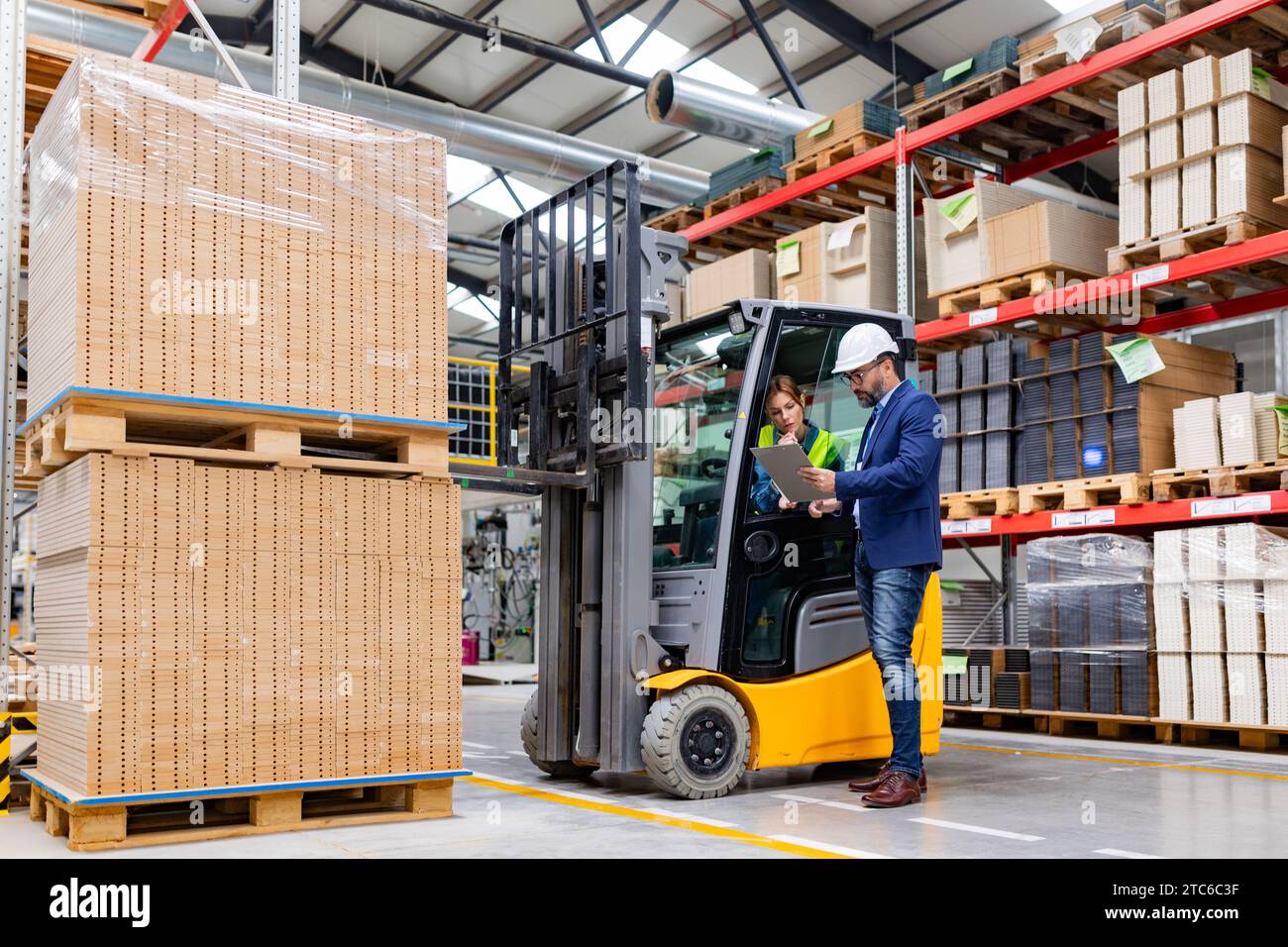 Forklift driver talking with manager in modern industrial factory ...