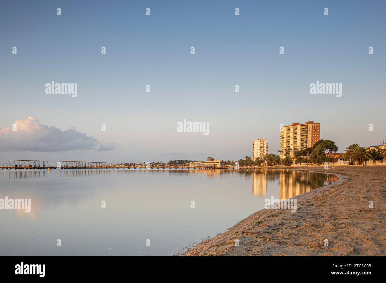 High rise building, along a Spanish beach, reflecting in the calm ocean ...