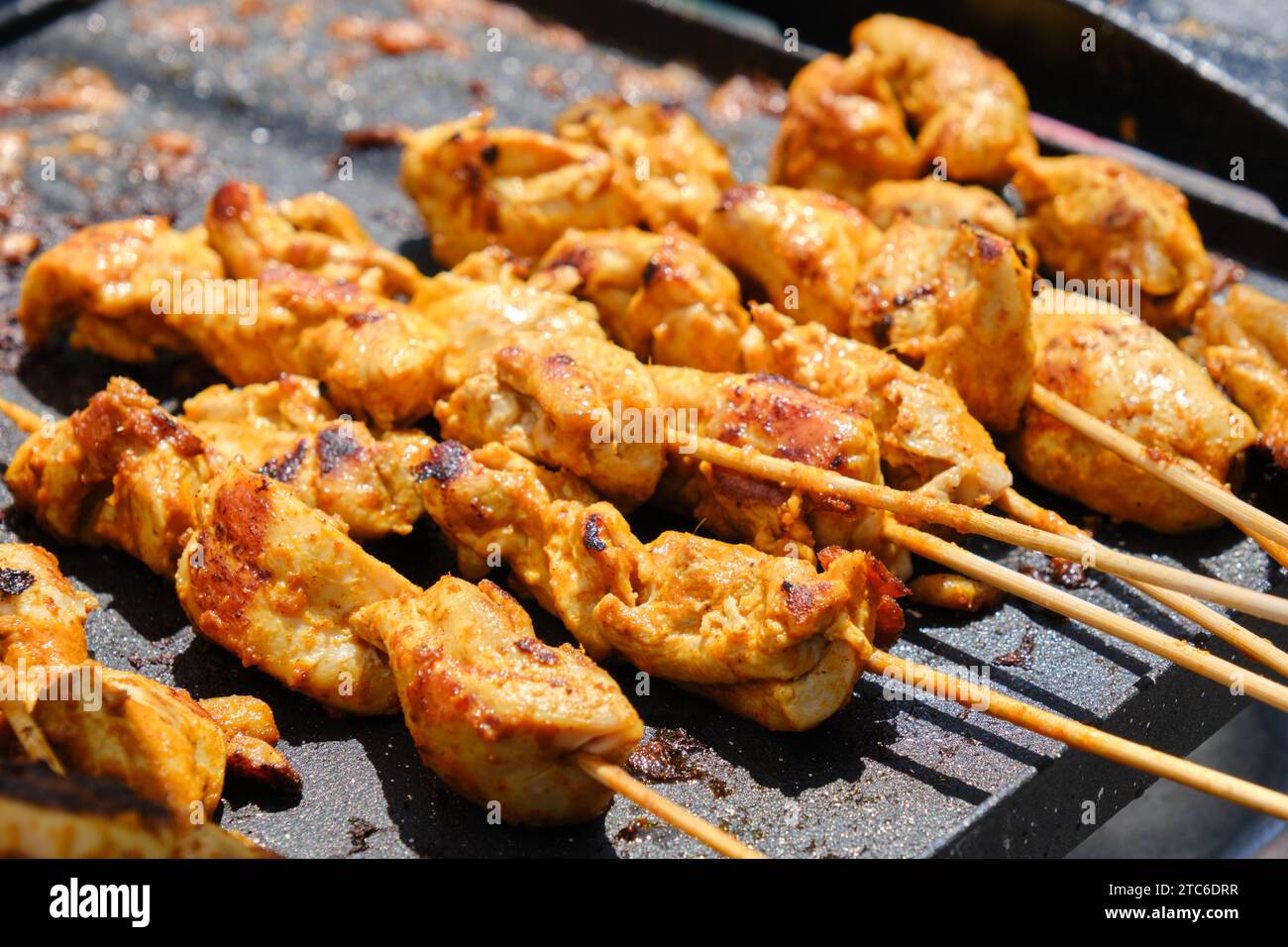 stacked skewers of chicken marinated kebab on a hot plate of food stand Stock Photo