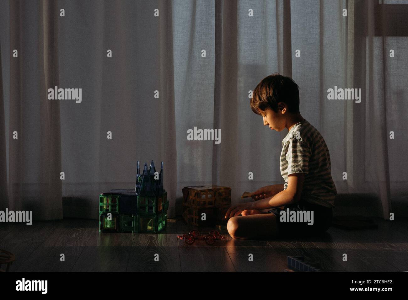 The boy plays the constructor on the floor in the sun Stock Photo