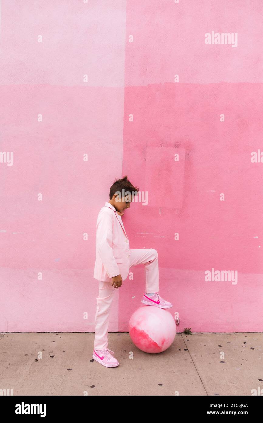 Young boy all pink with  a ball on the sidewalk in a suit Stock Photo