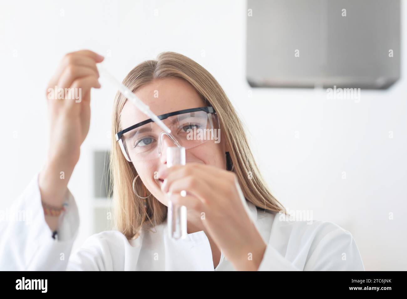 young scientist female with  lab glasses pipetting Stock Photo