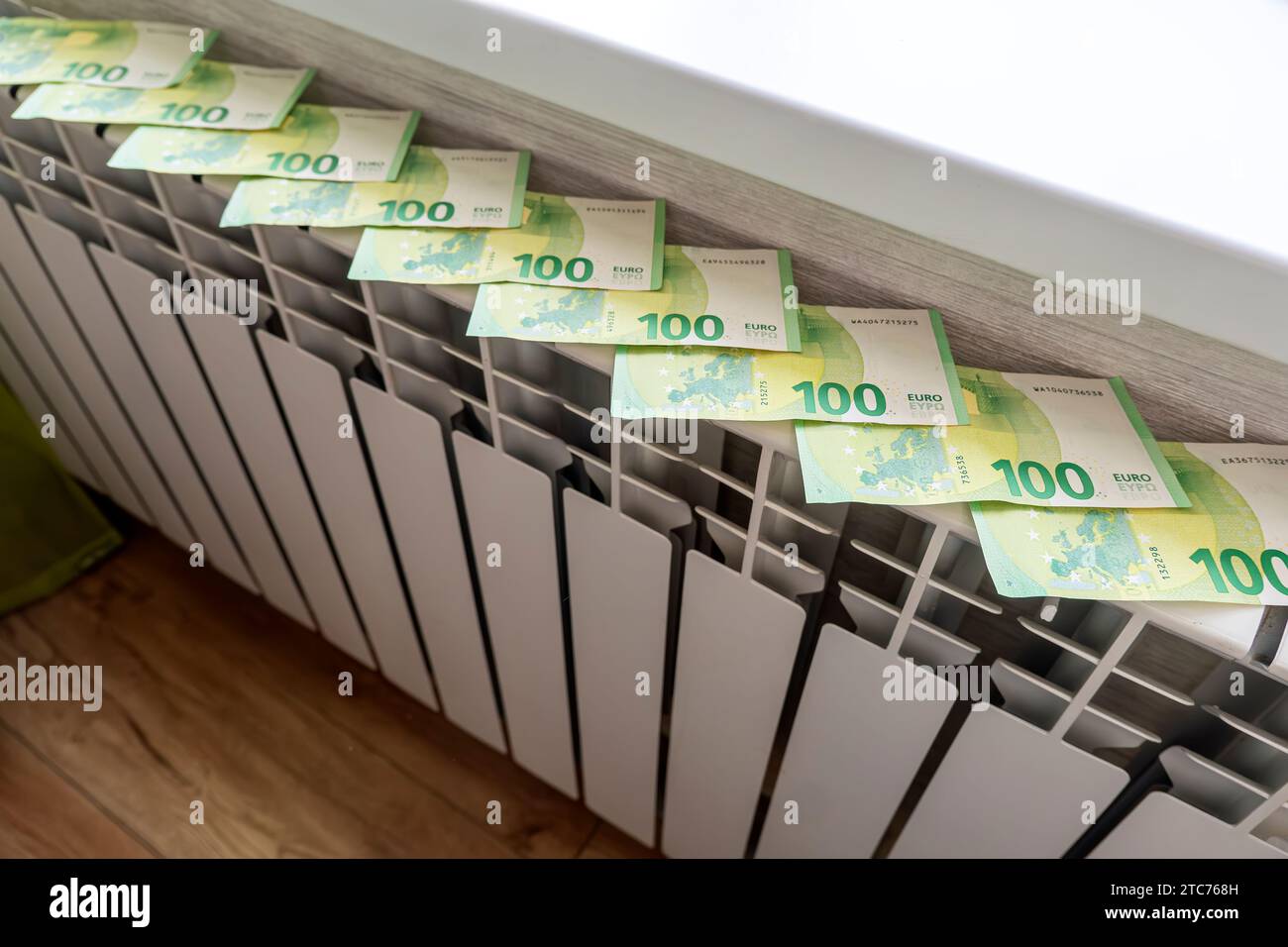 The concept of paying for heating in homes with a cold climate. Cash money is lying on a white metal radiator near the window. Stock Photo