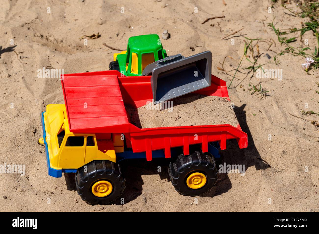 A small plastic toy truck that is loaded with sand by a toy wheel