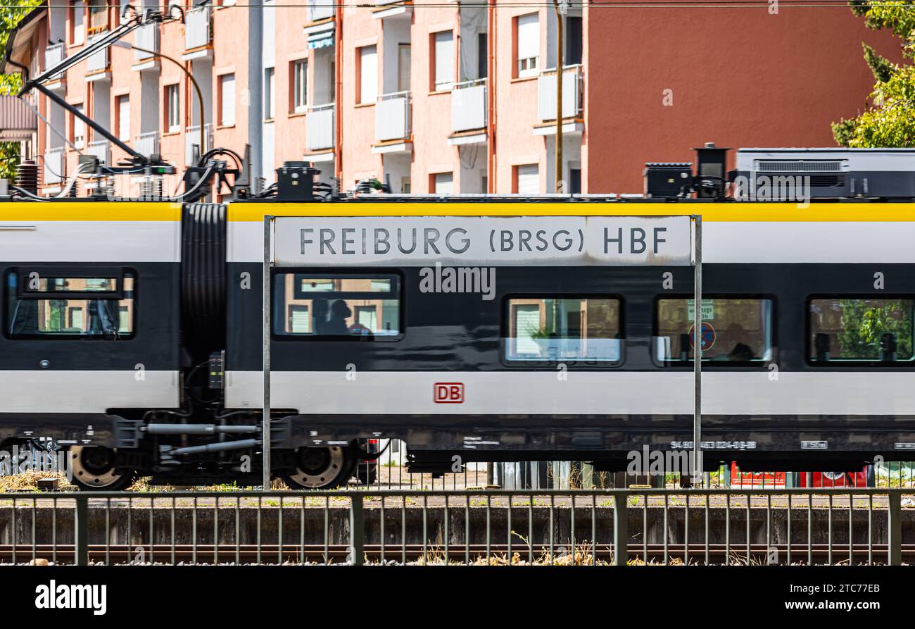Hauptbahnhof Freiburg Ein Schild der Freiburger Hauptbahnhof, dahinter fährt ein Zug der deutsche Bahn durch. Freiburg im Breisgau, Deutschland, 07.08.2022 *** Freiburg main station A sign of Freiburg main station, behind it a Deutsche Bahn train passes through Freiburg im Breisgau, Germany, 07 08 2022 Stock Photo
