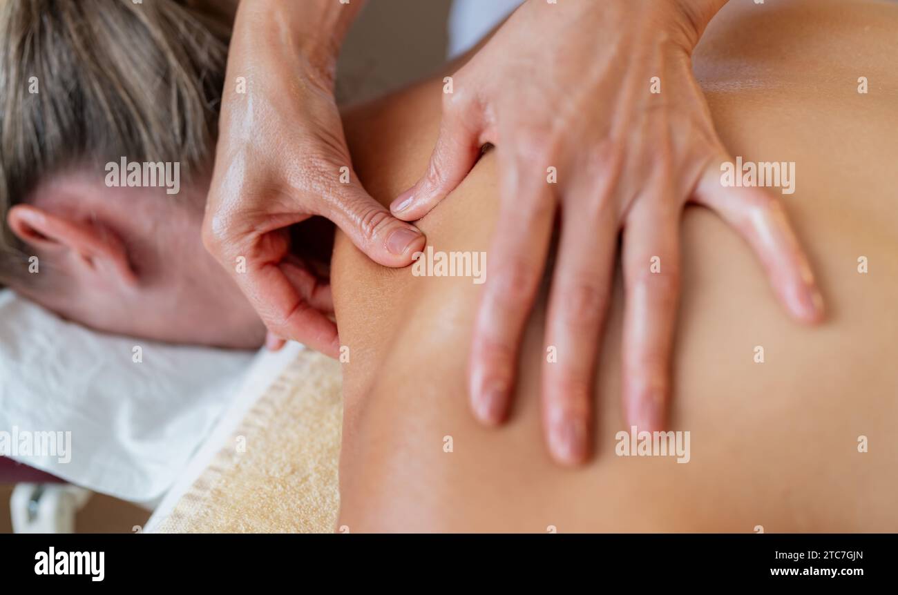 Close-up of a massage therapist applying pressure on a client's back Stock Photo