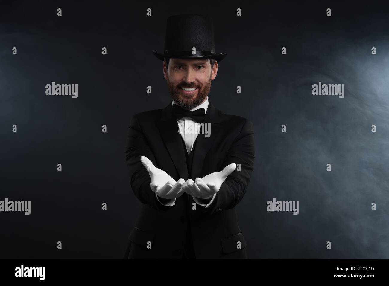 Happy magician wearing top hat in smoke on black background Stock Photo ...