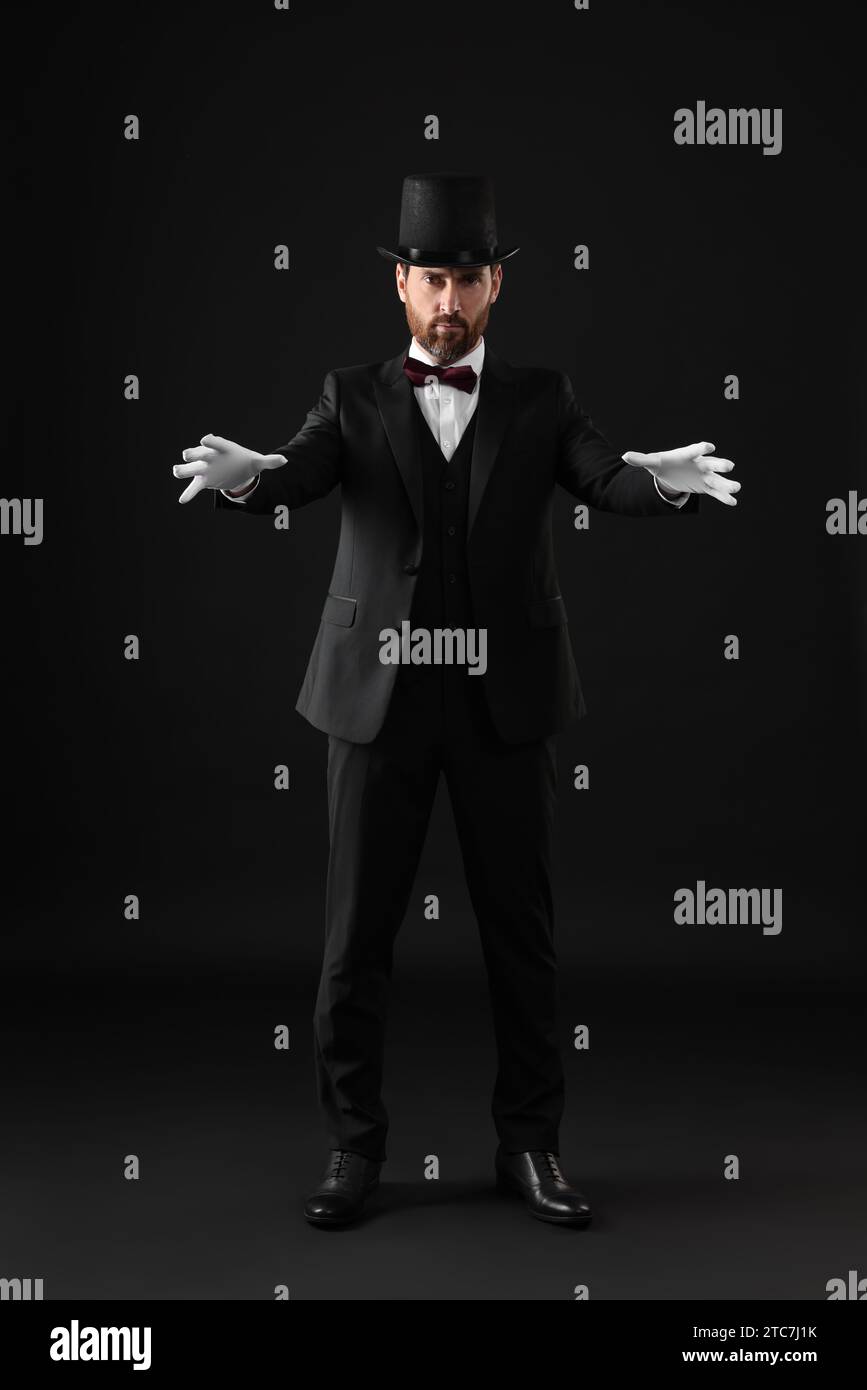 Magician in top hat on black background Stock Photo - Alamy