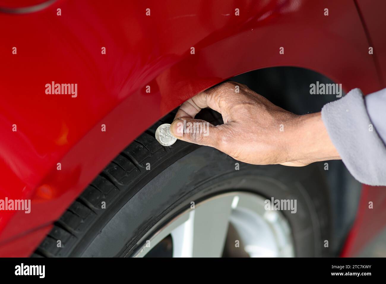 A black man using a coin to measure a tire tread Stock Photo Alamy