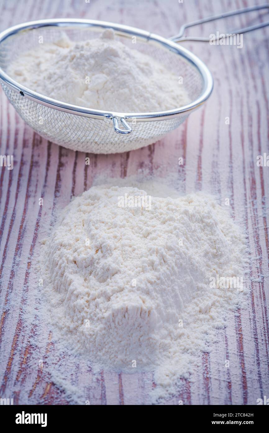 Stack of flour and sieve on vintage wooden board Stock Photo