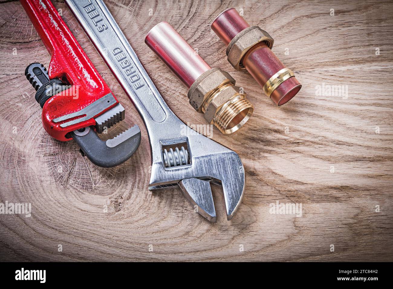 Copper water pipe wrench nipple hose connectors adjustable key on wooden board plumbing concept Stock Photo