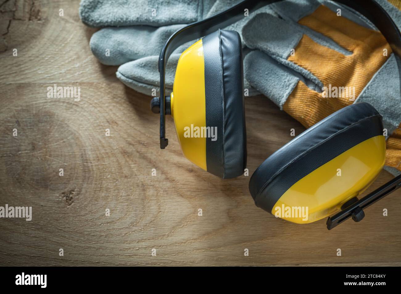 Noise reduction earmuffs protective gloves on wooden board Stock Photo