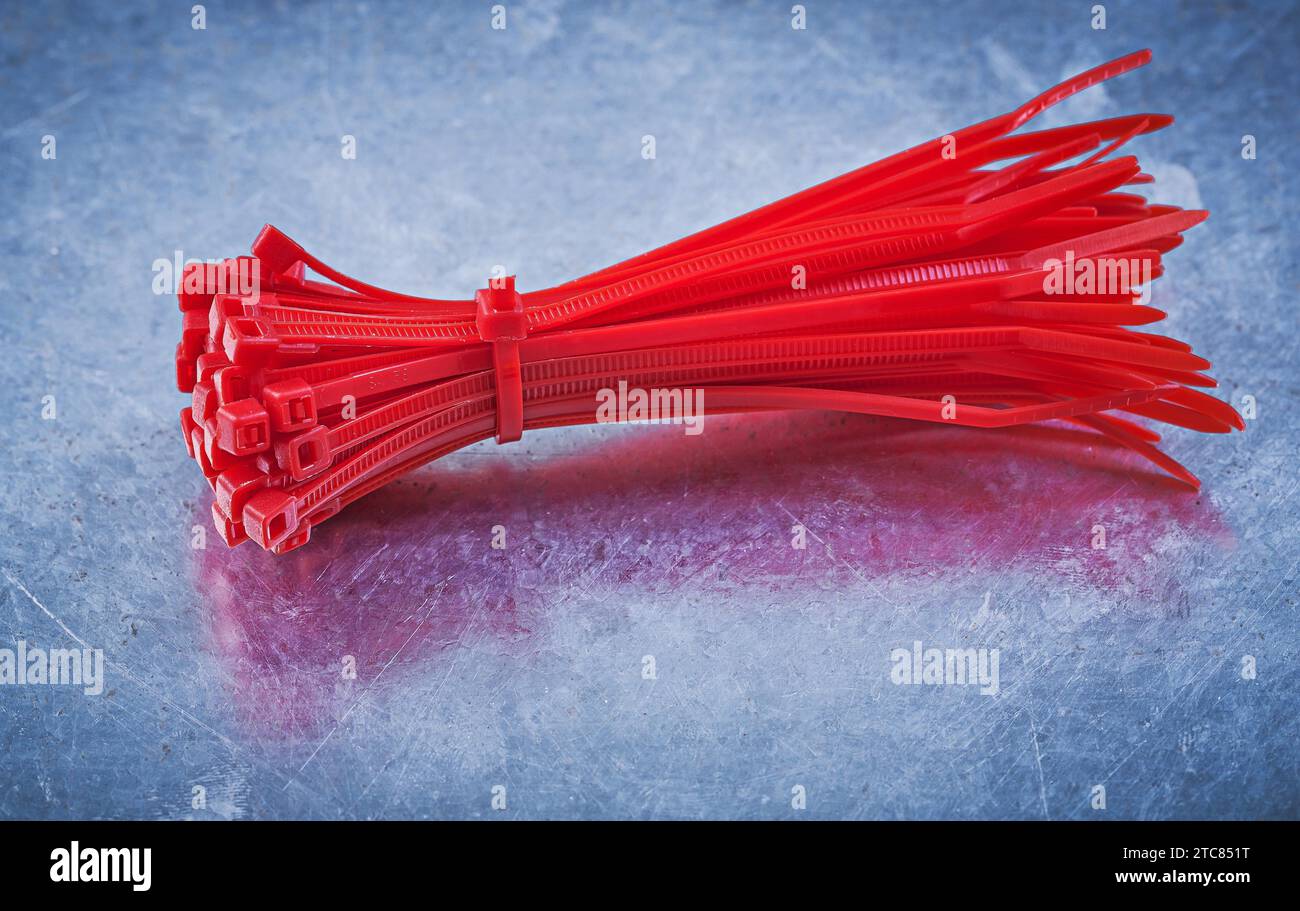 Red plastic self-locking cable ties on metallic background construction concept Stock Photo