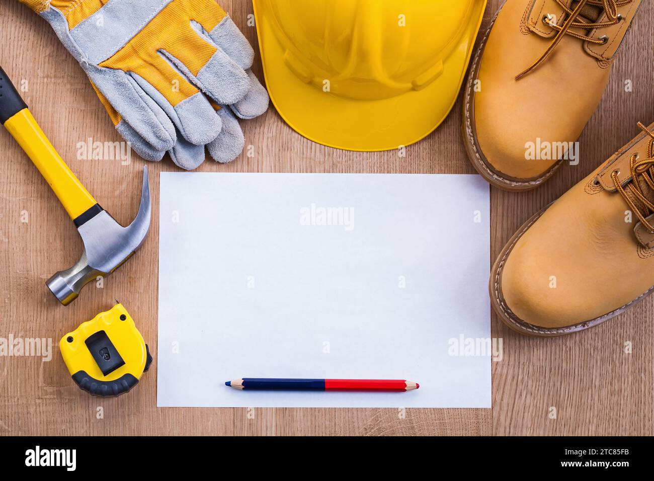 Pencil and paper tapeline hammer working boots helmet gloves on wooden board with copyspace Stock Photo
