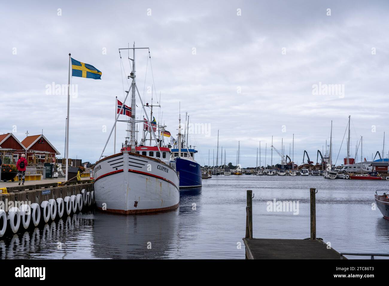 Recreational boats docked at a marina on a calm day, with their respective flags waving in the light breeze in Sweden Stock Photo