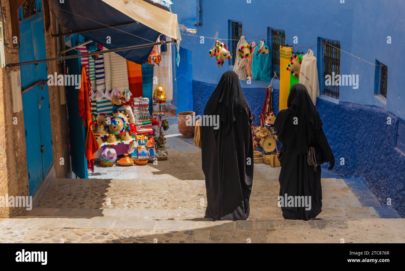 A picture of two women wearing a burka walking in an alley in Chefchaouen Stock Photo