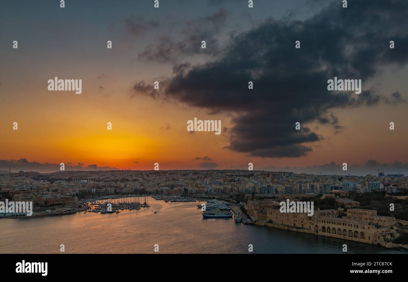 A picture of the sun setting over the coastal areas of G?ira & Ta' Xbiex, in Valletta Malta Stock Photo
