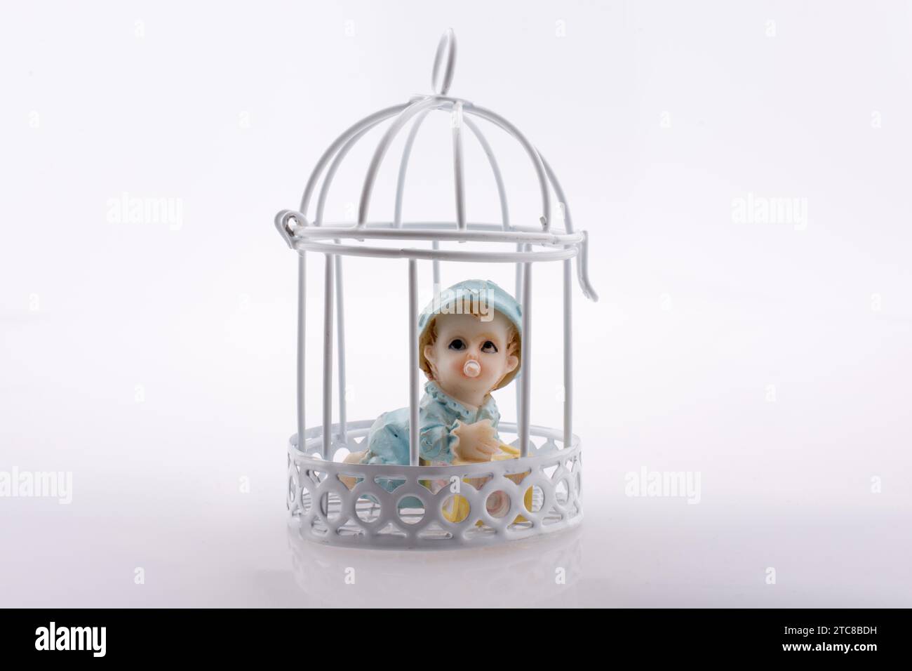 Little baby doll in cage on a white background Stock Photo