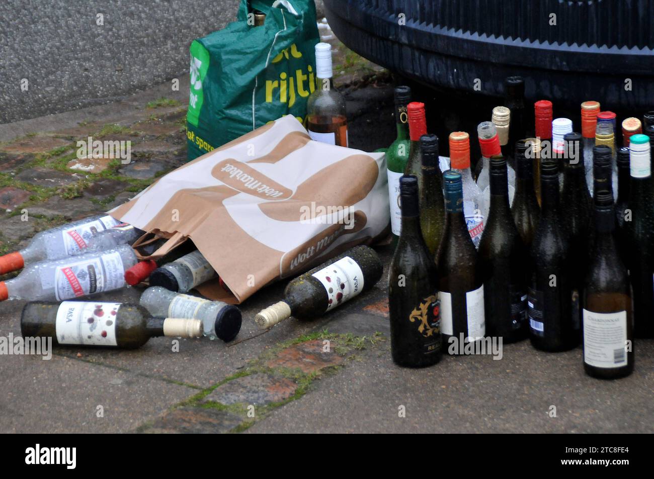 Copenhagen, Denmark /11 December 2023 /Empty wine bottle pile infront of recycle container
