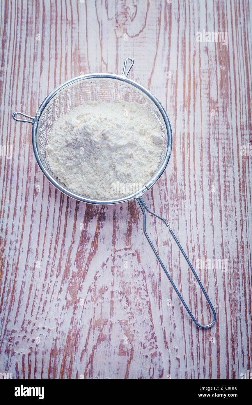 Single sieve with white natural flour on vintage wooden board Stock Photo