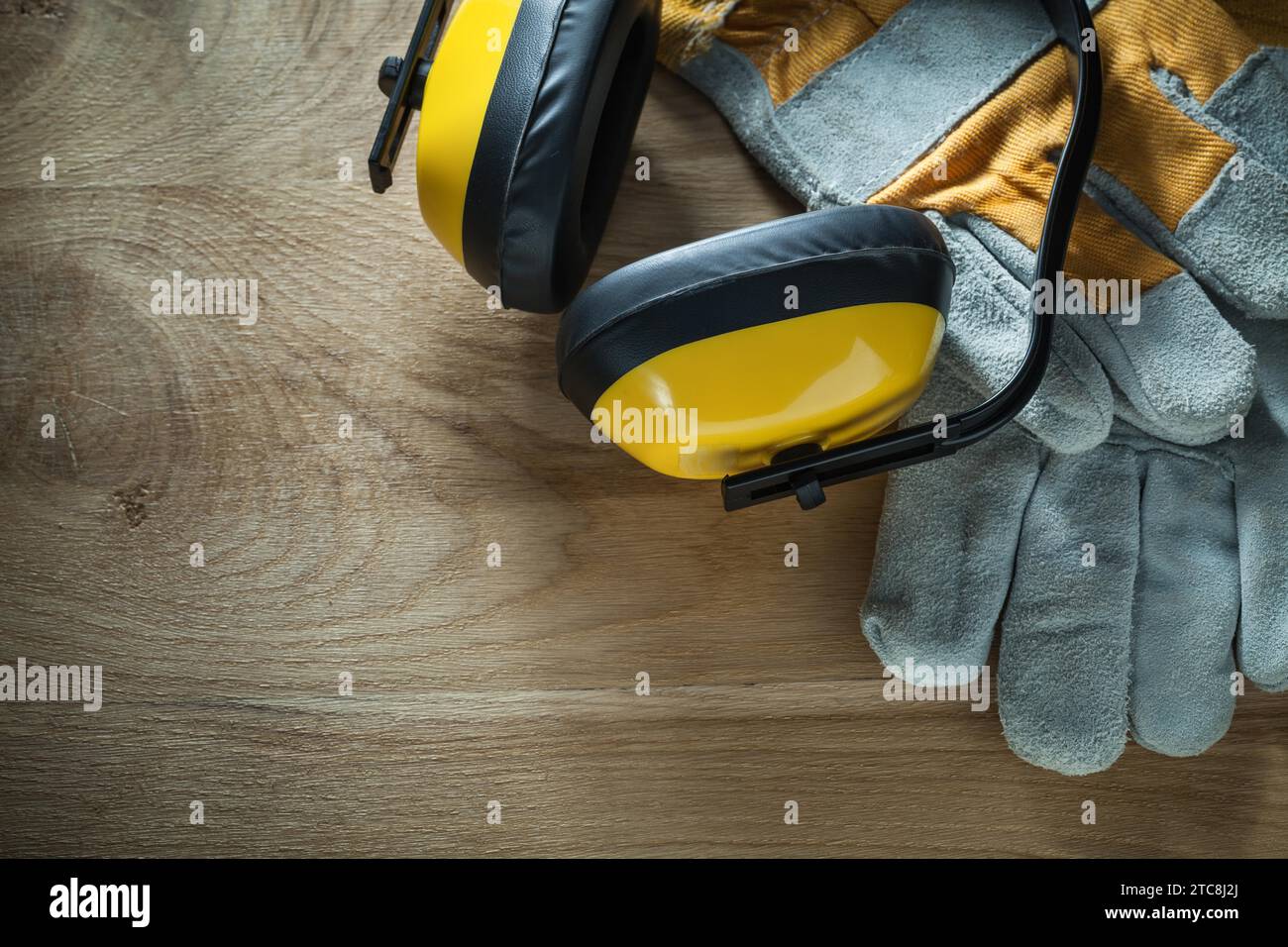 Noise reduction earmuffs safety gloves on wooden board Stock Photo