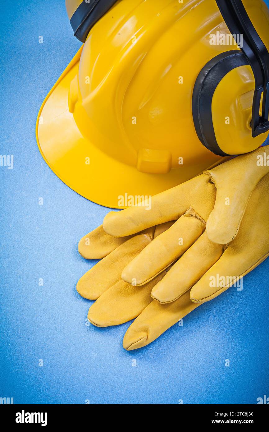 Noise reduction ear muffs safety gloves hard hat on blue background