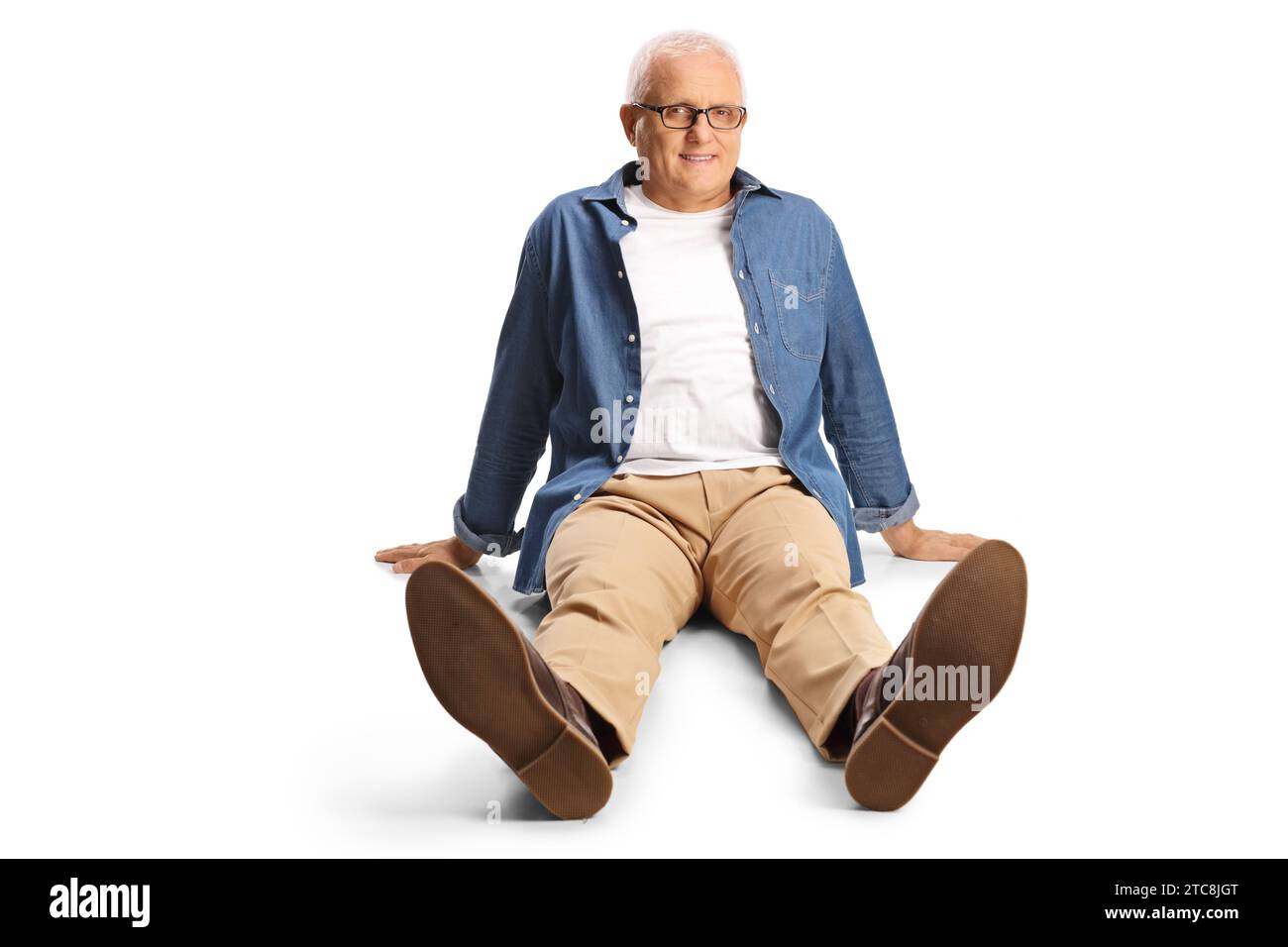 Smiling mature man sitting on the floor isolated on white background ...