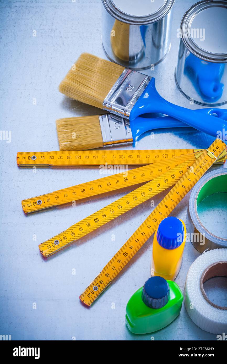 Construction paint tools with duct tapes and wooden meter on metallic