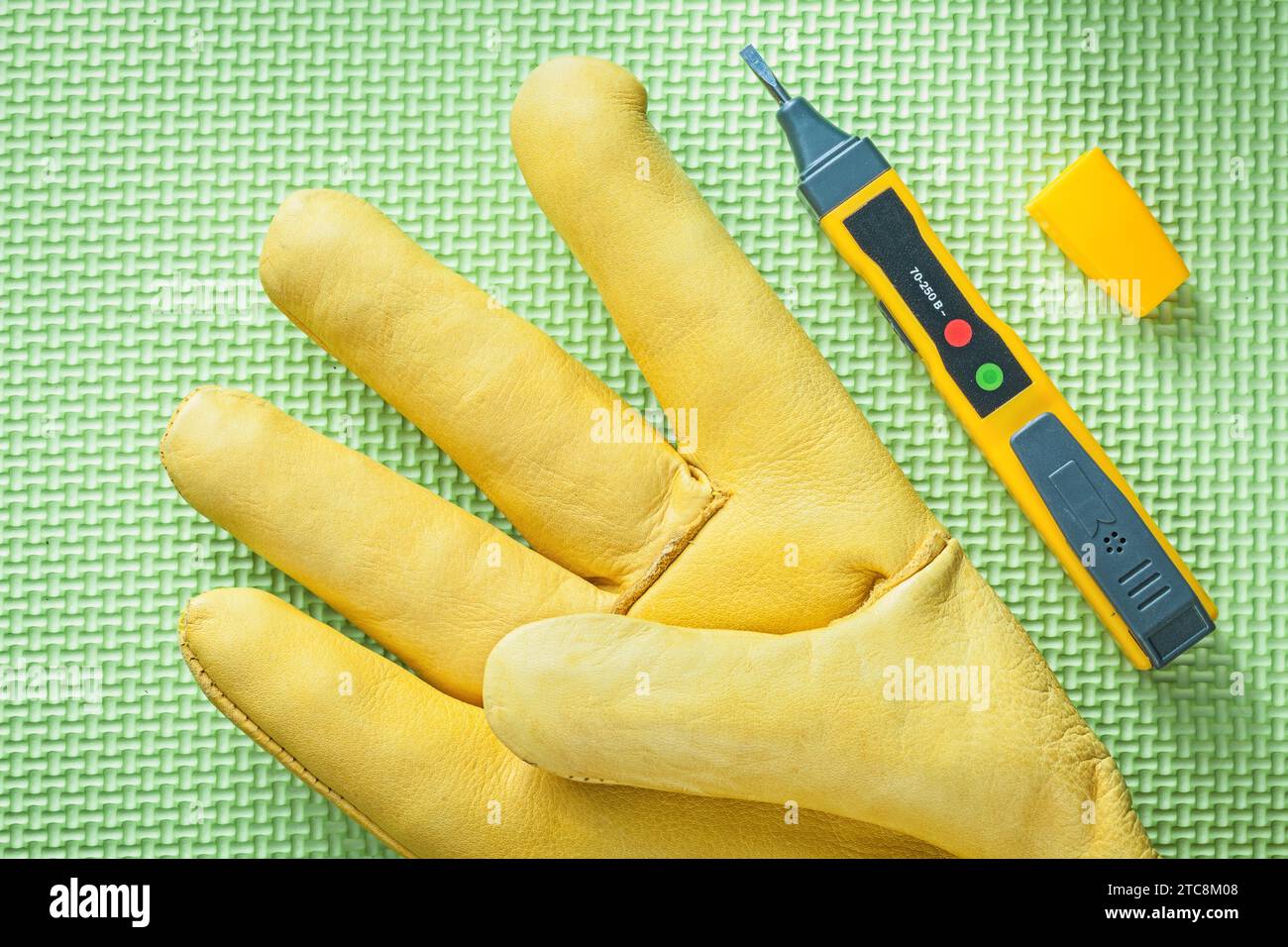 Leather safety glove electrical tester on green surface electricity
