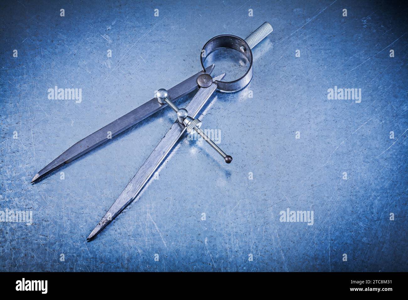 Metal construction pair of compasses on scratched metallic background Stock Photo