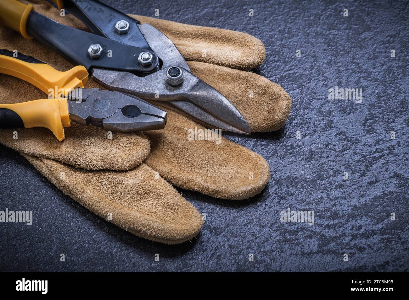 Sharp tin snips pliers leather safety glove on black background Stock