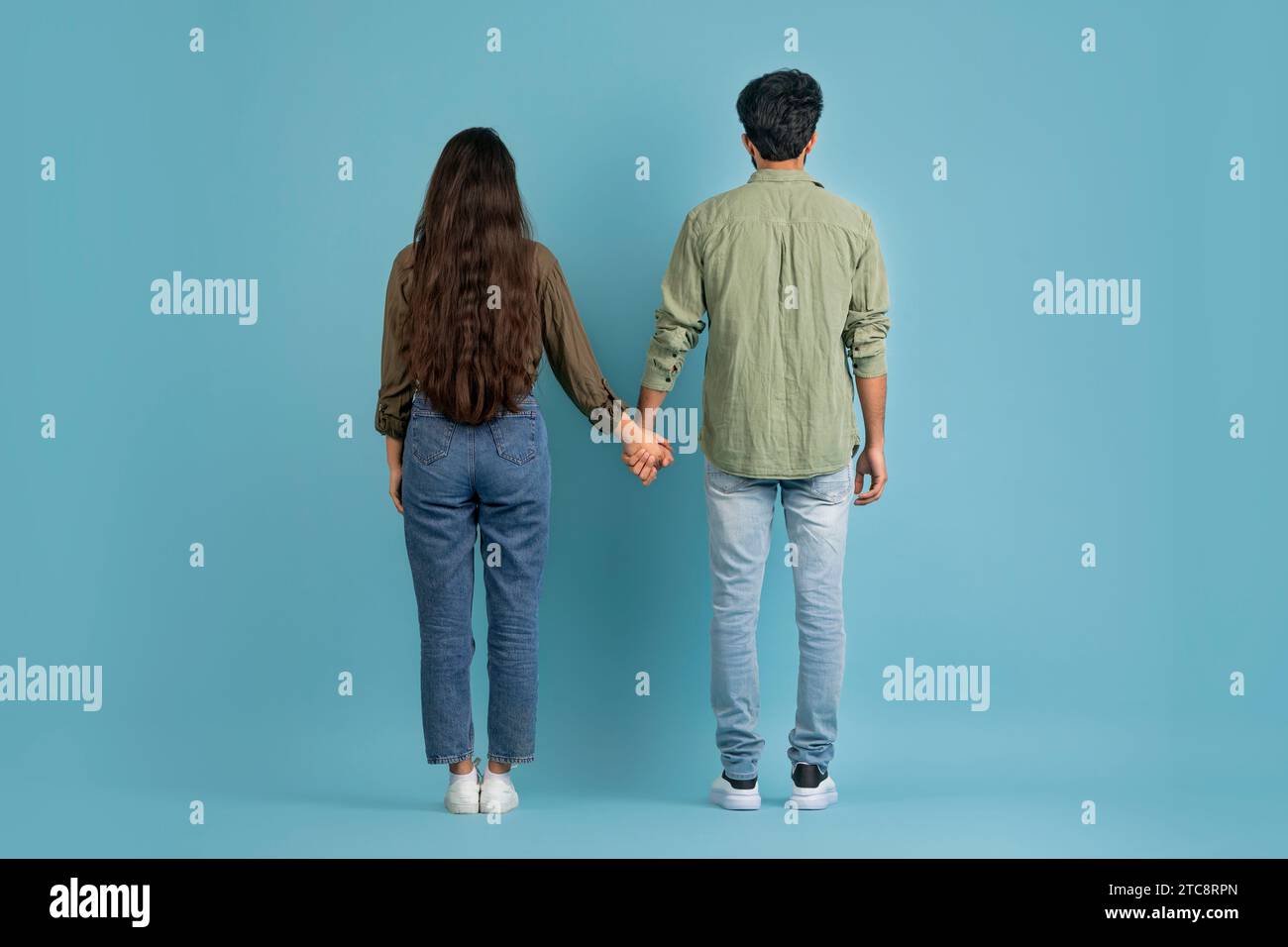 Back view of millennial couple posing on blue background Stock Photo