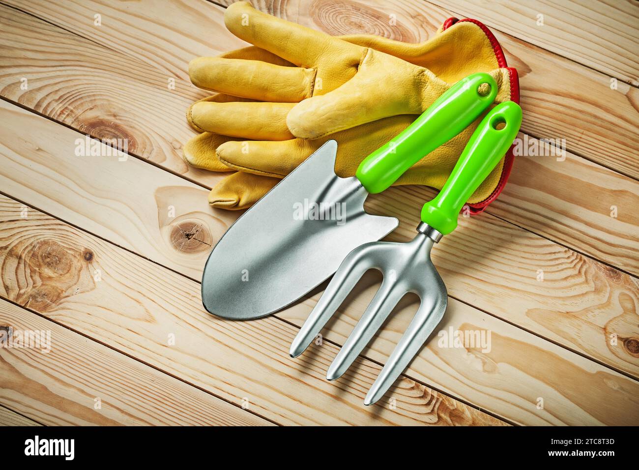 Hand spade and garden fork with yellow leather gloves on wood Stock Photo