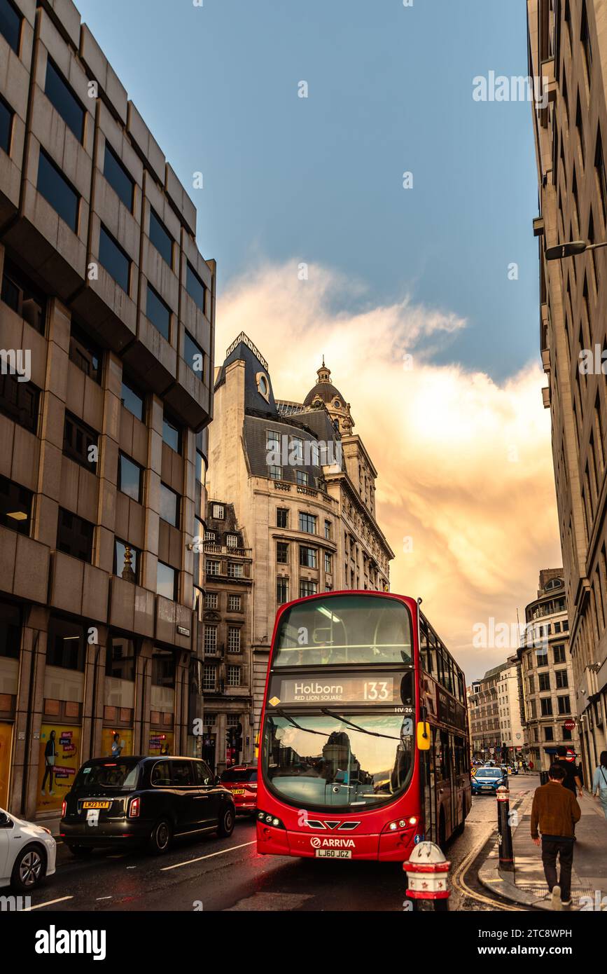 London, UK - August 25, 2023: Double decker red bus speeding up in Cannon Street at dusk Stock Photo