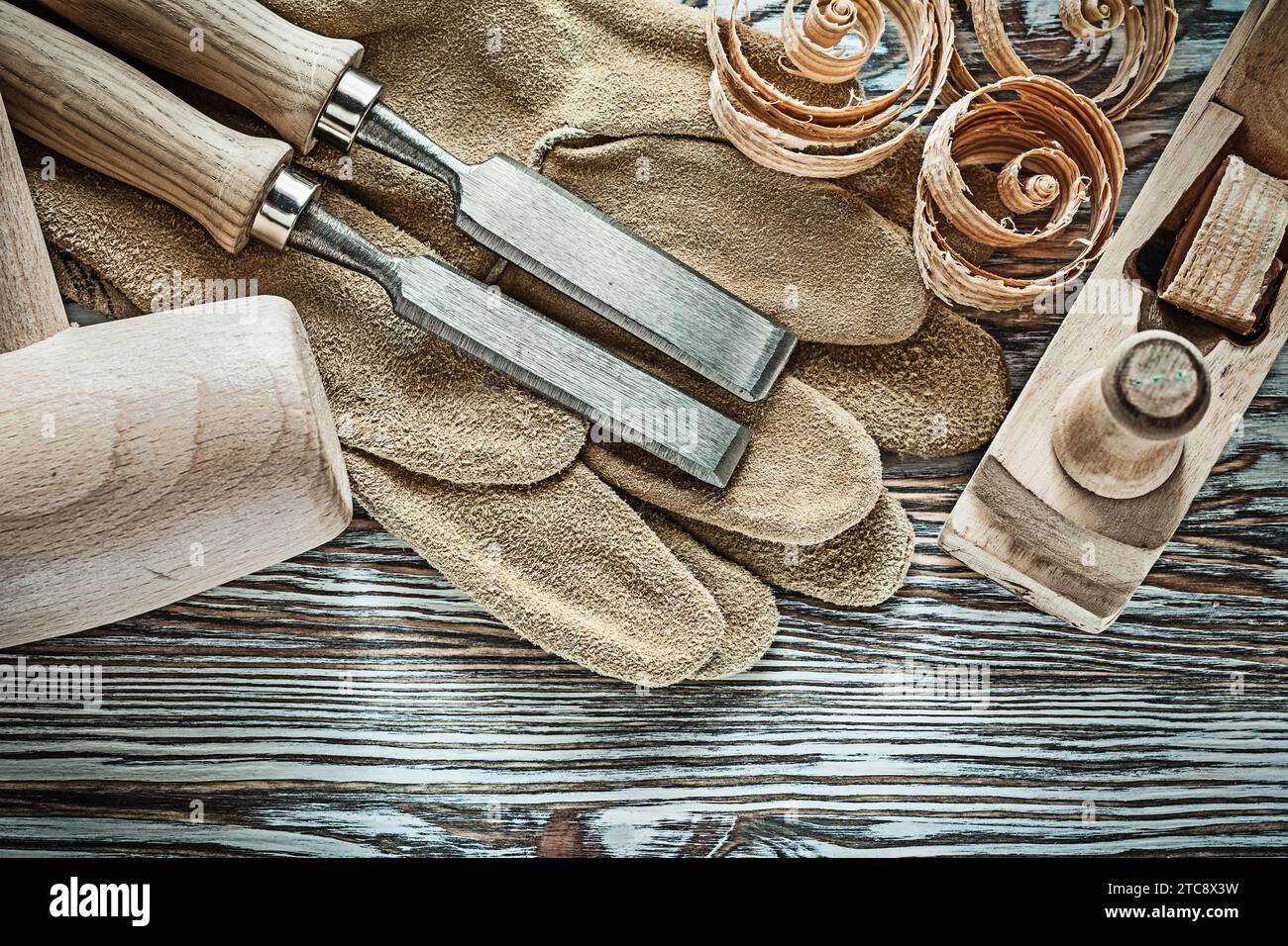 Leather protective gloves Lump hammer Flat chisel Shaving plane Wood shavings Stock Photo