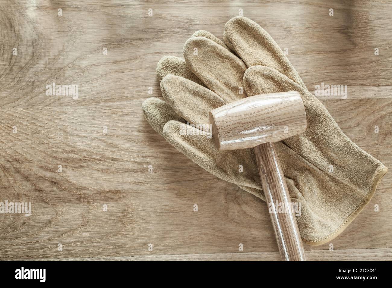 Leather protective gloves Block hammer on wooden board Stock Photo