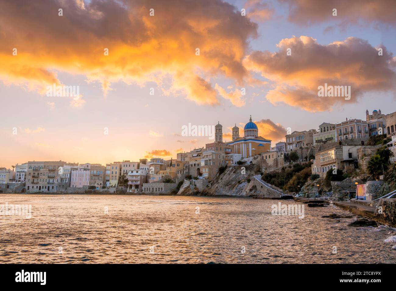 View of the village with the Greek Orthodox church of Agios Nikolaos, Asteria Beach, at sunset with atmospheric clouds, Ermoupoli, Syros, Cyclades Stock Photo