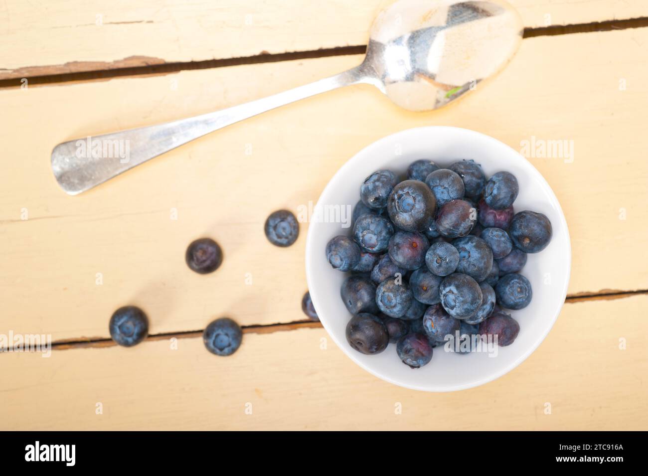 Fresh blueberry on a bowl with silver spoon over wood table Stock Photo