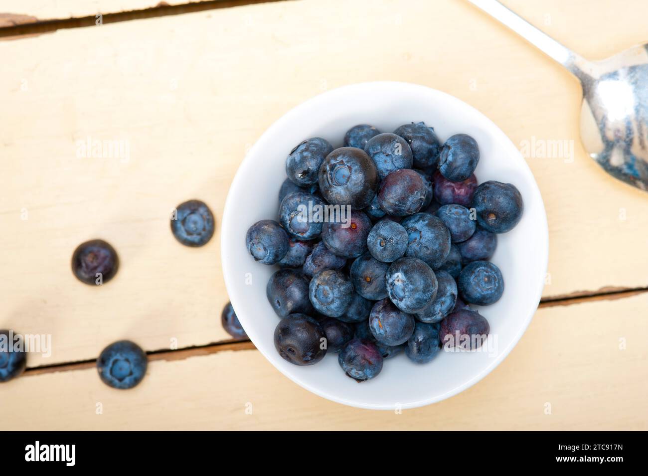 Fresh blueberry on a bowl with silver spoon over wood table Stock Photo
