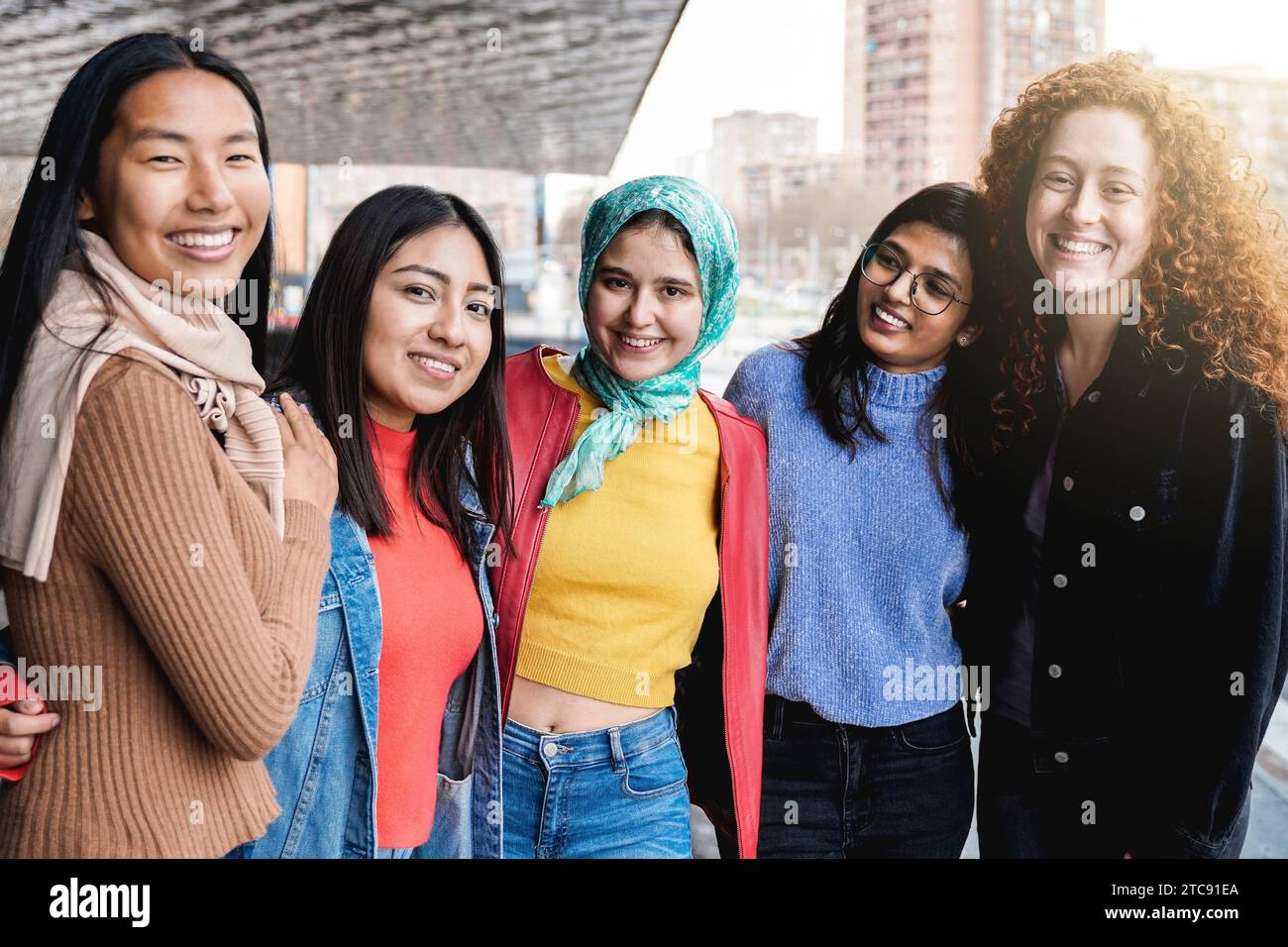 Diverse female friends having fun togehter on city street. Group of multiracial people smiling and hugging on camera Stock Photo