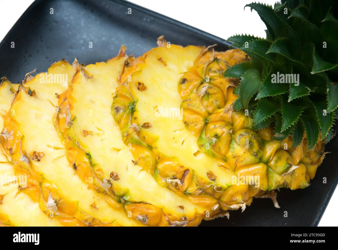 Ripe vibrant pineapple sliced on a black plate Stock Photo