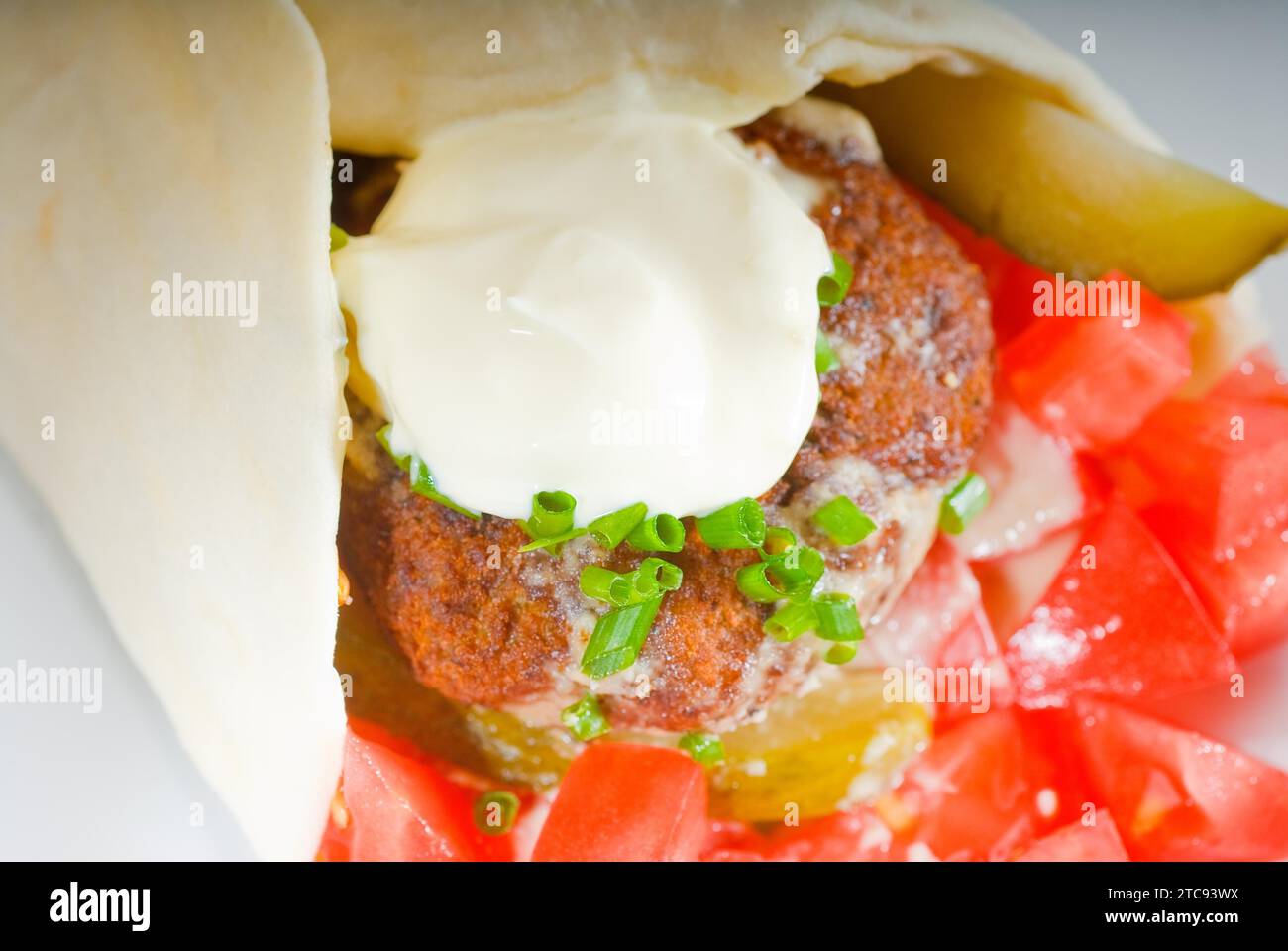 Fresh traditional falafel wrap on pita bread with fresh chopped tomatoes Stock Photo